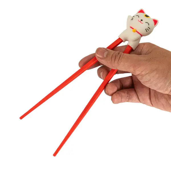 Hand holding red training chopsticks with a white lucky cat topper - PABOOM
