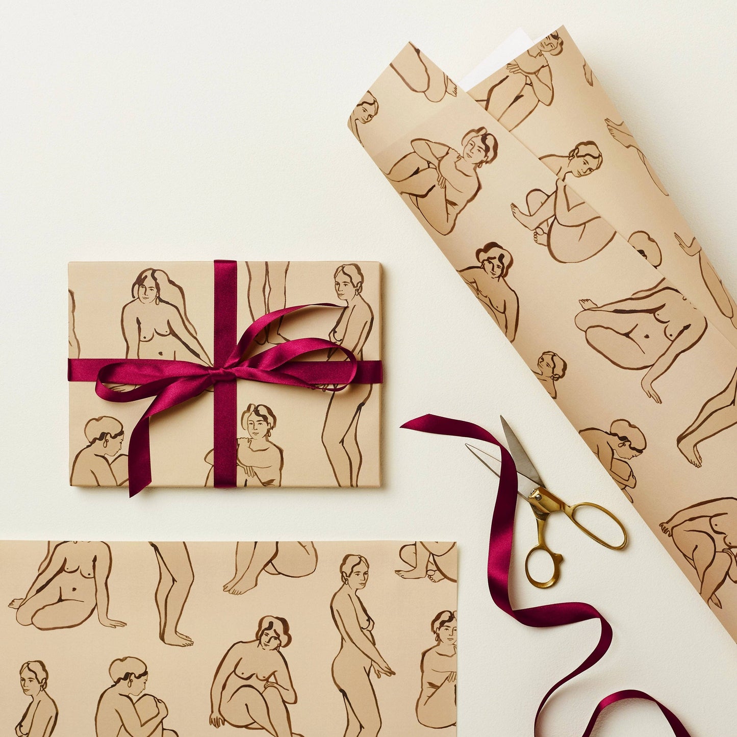 Wrapping paper printed with brown line-art nude figures on a kraft background, tied with burgundy ribbon