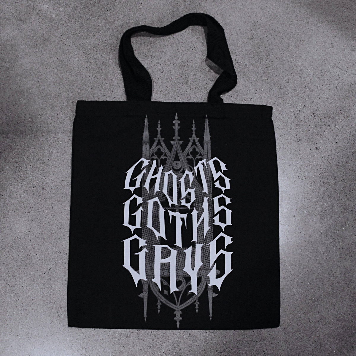 Black cotton canvas tote bag with gothic cathedral-style lettering reading Ghosts, Goths, Gays printed in grey and white across the front