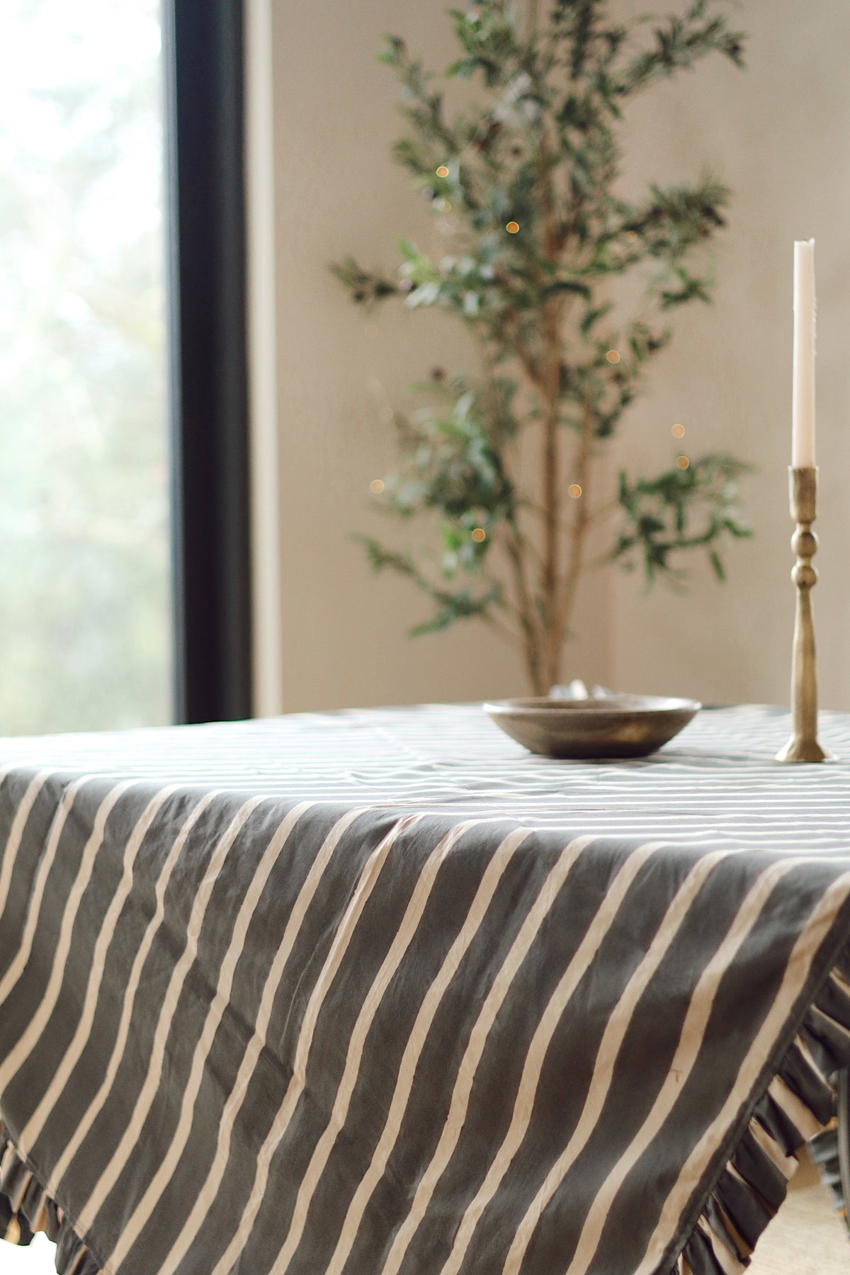 Block Print Stripe Ruffle Tablecloth in Charcoal draped on a table corner