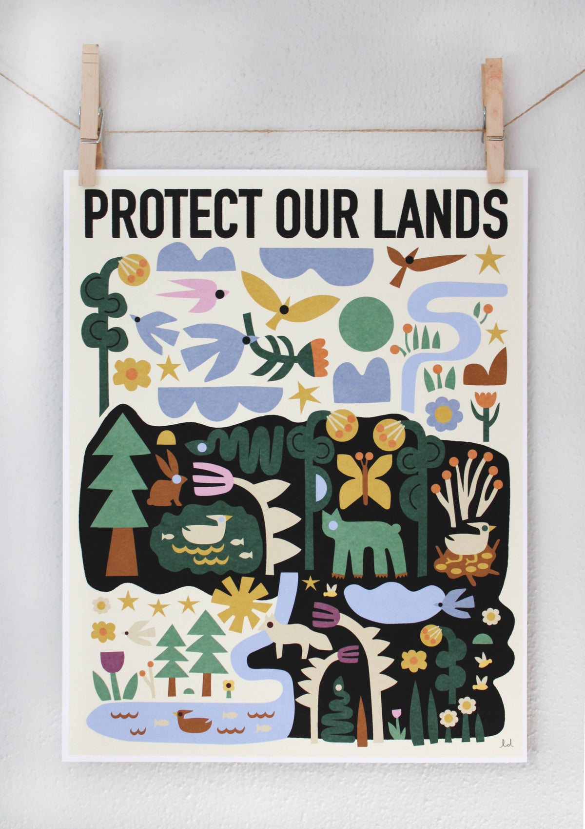 Protect Our Lands archival print with a folk-art forest and river scene featuring deer, rabbits, and birds, clipped to a string β PABOOM
