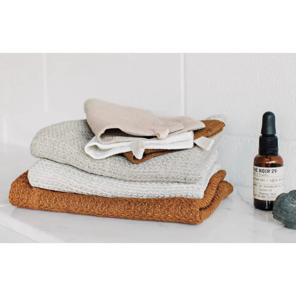 Danica - Amber Linen Hand Towel - stacked folded towels skincare bottle