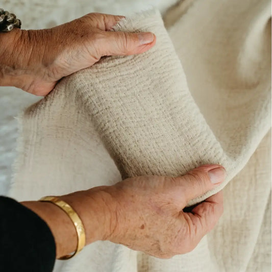Natural Malabar throw by Indaba with two hands holding a section to show texture