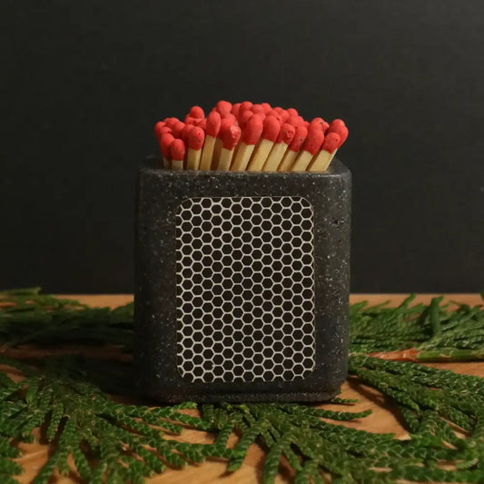 Concrete black cube match holder with strike pad on side, matches inside