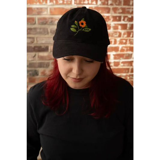 Person wearing Black baseball hat with embroidered flower stem and leaves. Cotton, black. - PABOOM