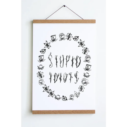 Floral black font saying STUPID IDIOTS surrounded by flower outlines on a white background print - PABOOM