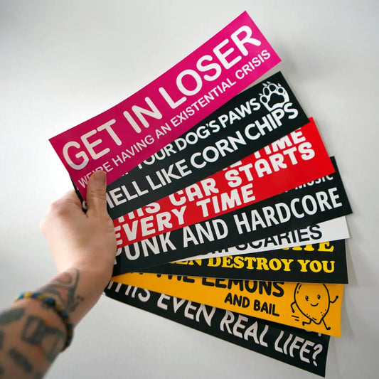 A hand holding 8 bumper stickers from Stuntin Goods - PABOOM