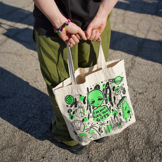 Canvas tote bag with aliens and supernatual designs being held by person