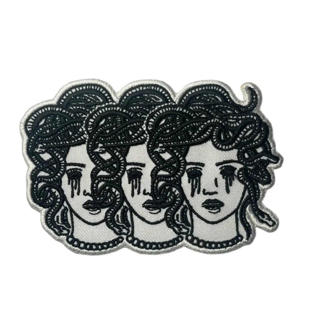 Iron on embroidered patch of three medusa heads with blacked out crying eyes.