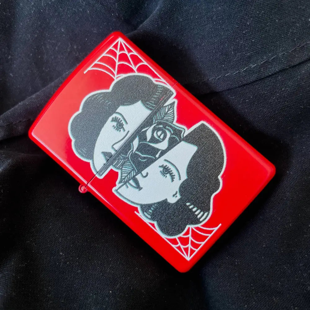 Zippo red lighter with a woman’s face splint in half with rose in middle on black fabric