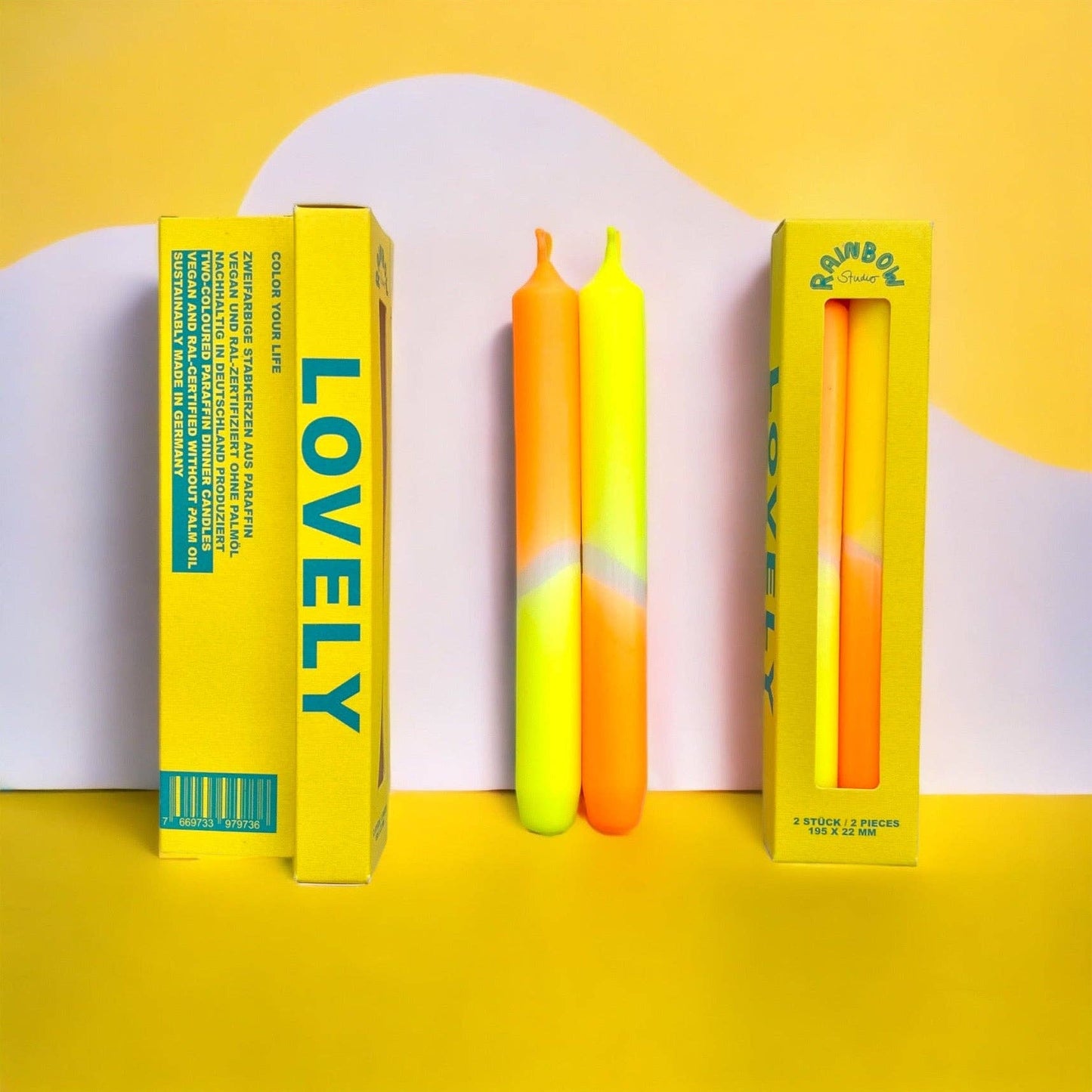 Rainbow Studio Dinner Candle Set Lovely — two dip-dyed taper candles in yellow-to-orange gradient, shown beside yellow packaging