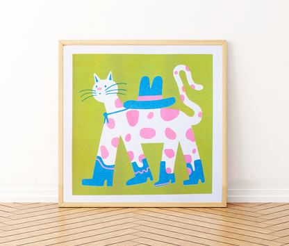 Cowboy Cat Square Risograph Art Print — illustration of a pink-spotted cat wearing a blue cowboy hat and boots, shown framed