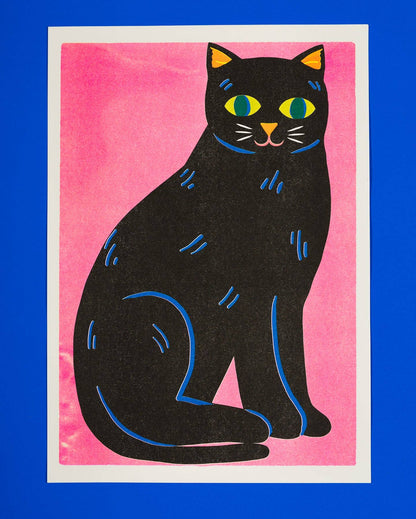 Risograph print of a black cat with green eyes on a hot pink background - PABOOM