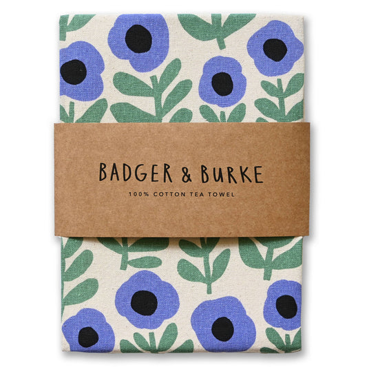 Folded natural cotton tea towel printed with periwinkle poppies and green leaves, Badger + Burke kraft band - PABOOM