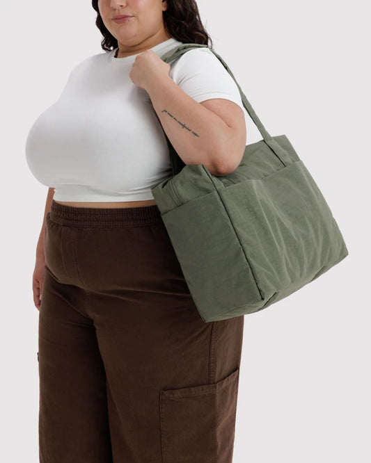 Model carrying the BAGGU Small Cloud Carry-On in caper green over one shoulder