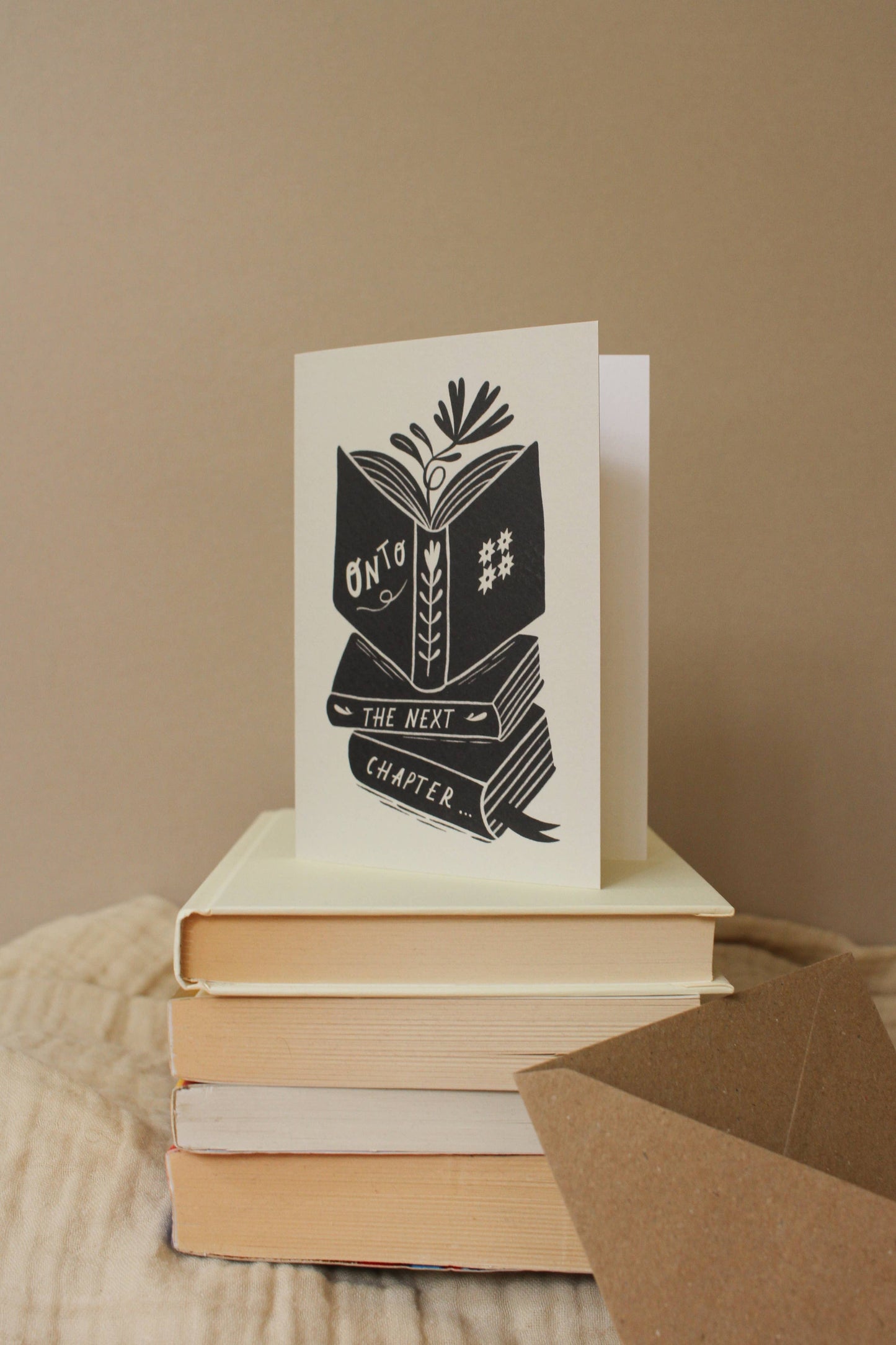 Close-up of the illustrated book stack detail on 'Onto The Next Chapter...' card