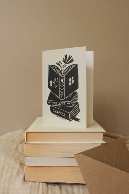 Close-up of the illustrated book stack detail on 'Onto The Next Chapter...' card