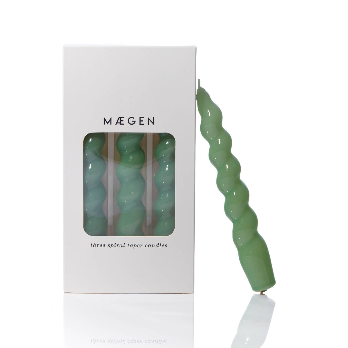 MÆGEN spiral taper candle in sage green leaning against its white branded box printed "three spiral taper candles"