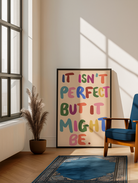 Framed "It Isn't Perfect But It Might Be" colorful typography art print leaning against a wall beside a plant and blue armchair - PABOOM