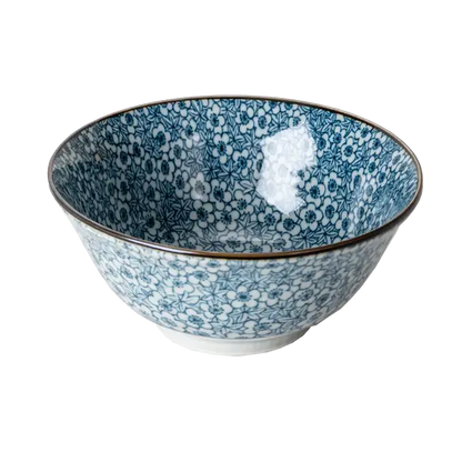Blue and white porcelain bowl covered in a dense komon-style floral print, viewed from a slight angle