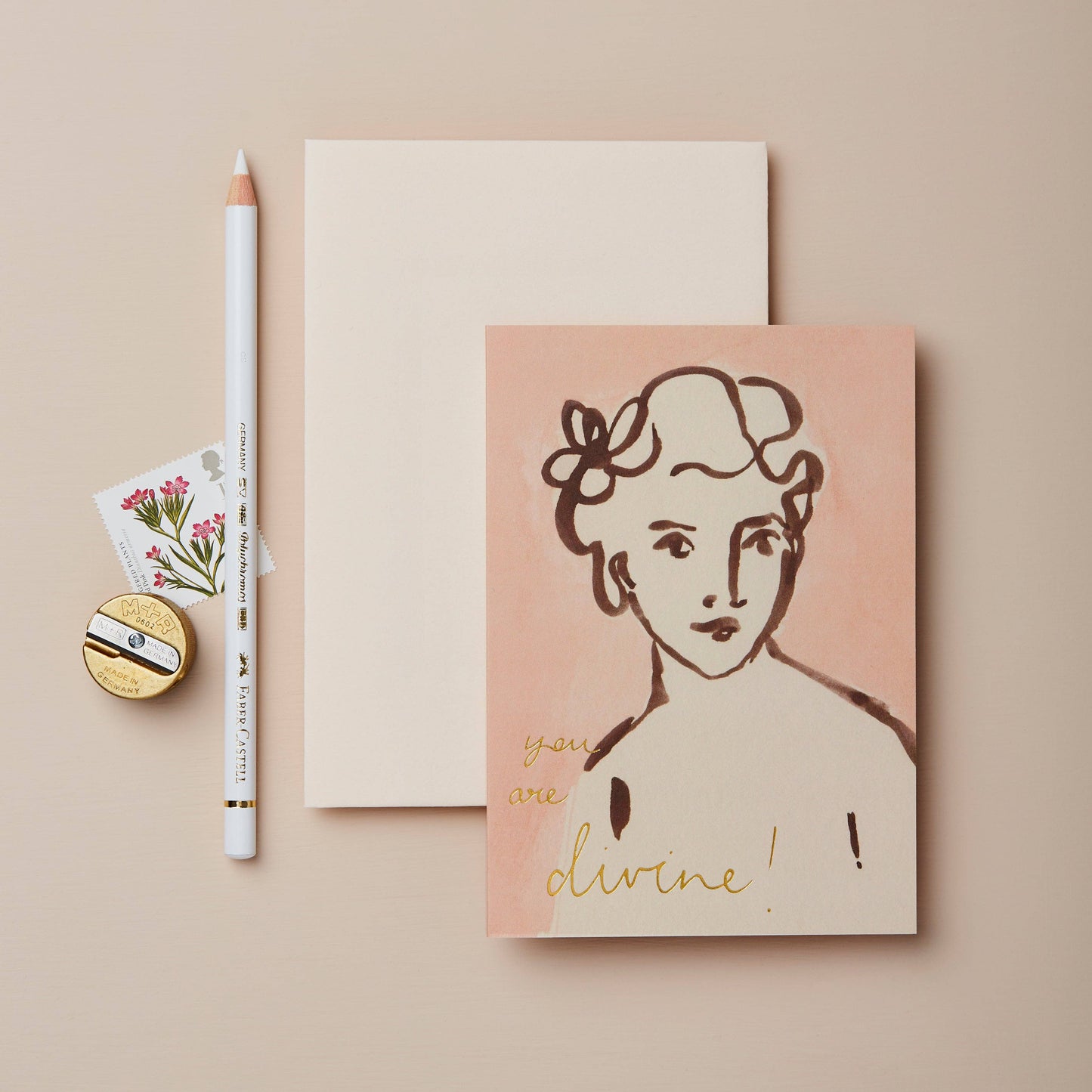 Blush pink card with a painted portrait of a woman, reading You Are Divine in gold script