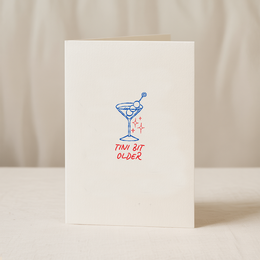 Blue Iris Designs Co birthday card with a hand-drawn blue martini glass and sparkle details, text reads "tini bit older" - PABOOM