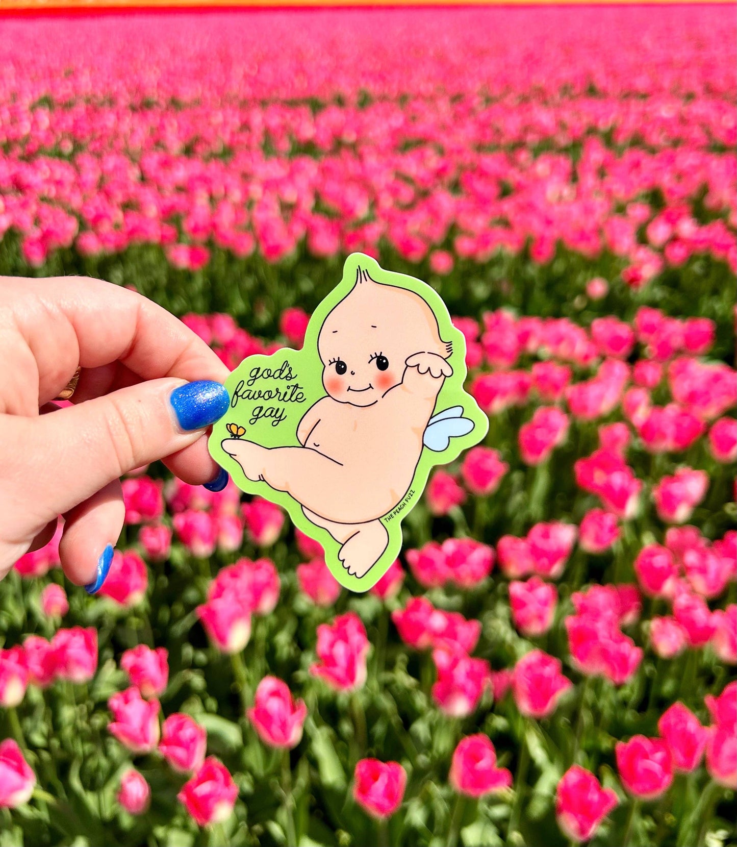 Green-outlined vinyl sticker of a Kewpie cherub angel with wings, reading god's favorite gay