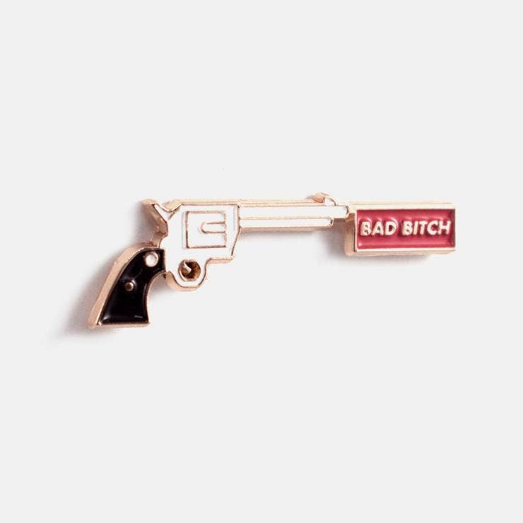 Gold enamel pin shaped like a revolver with the words Bad Bitch on the barrel - PABOOM
