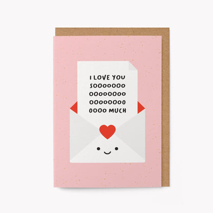 Pink greeting card with an illustrated smiling envelope holding a note that reads 'I love you soooo much,' kraft envelope alongside