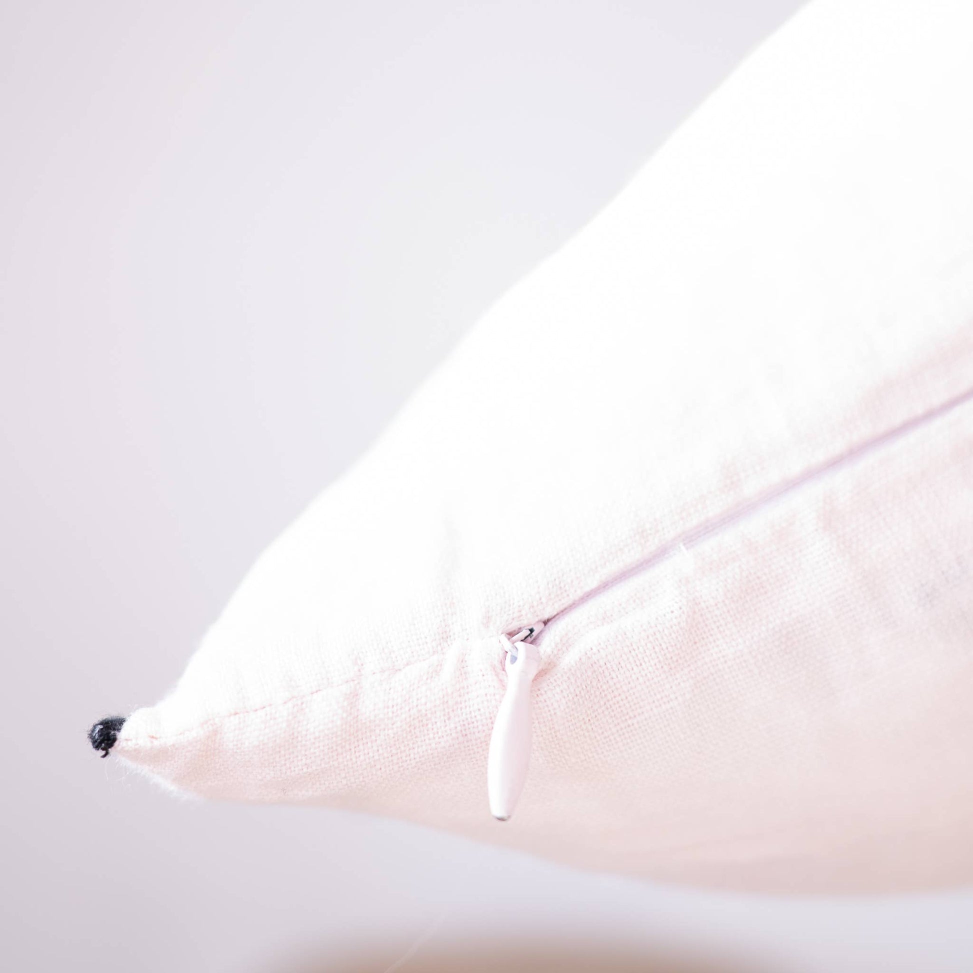 Blush edged linen lumbar pillow cover styled on a sofa or bed
