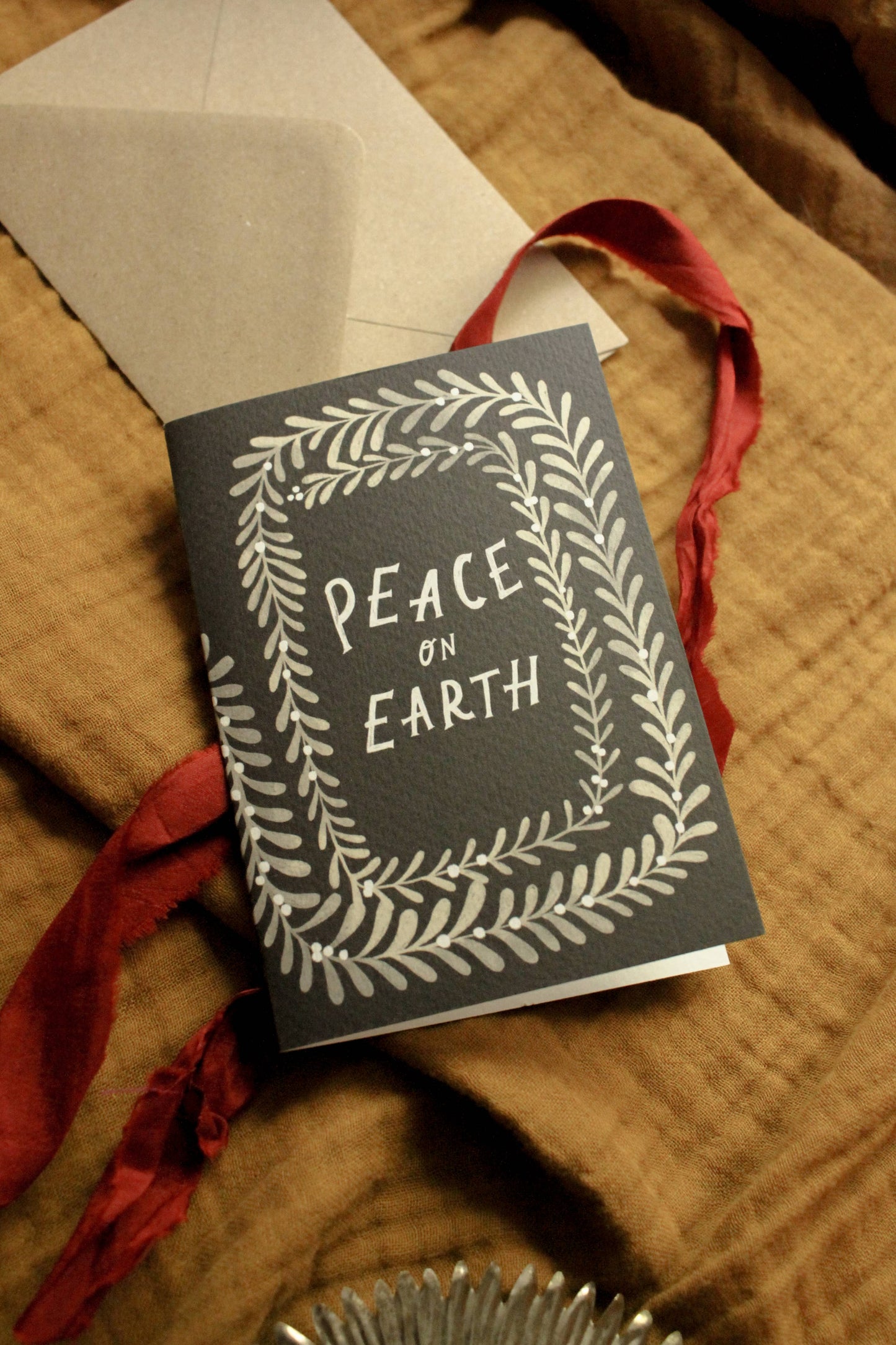'Peace on Earth' Christmas card with kraft envelope on a light background
