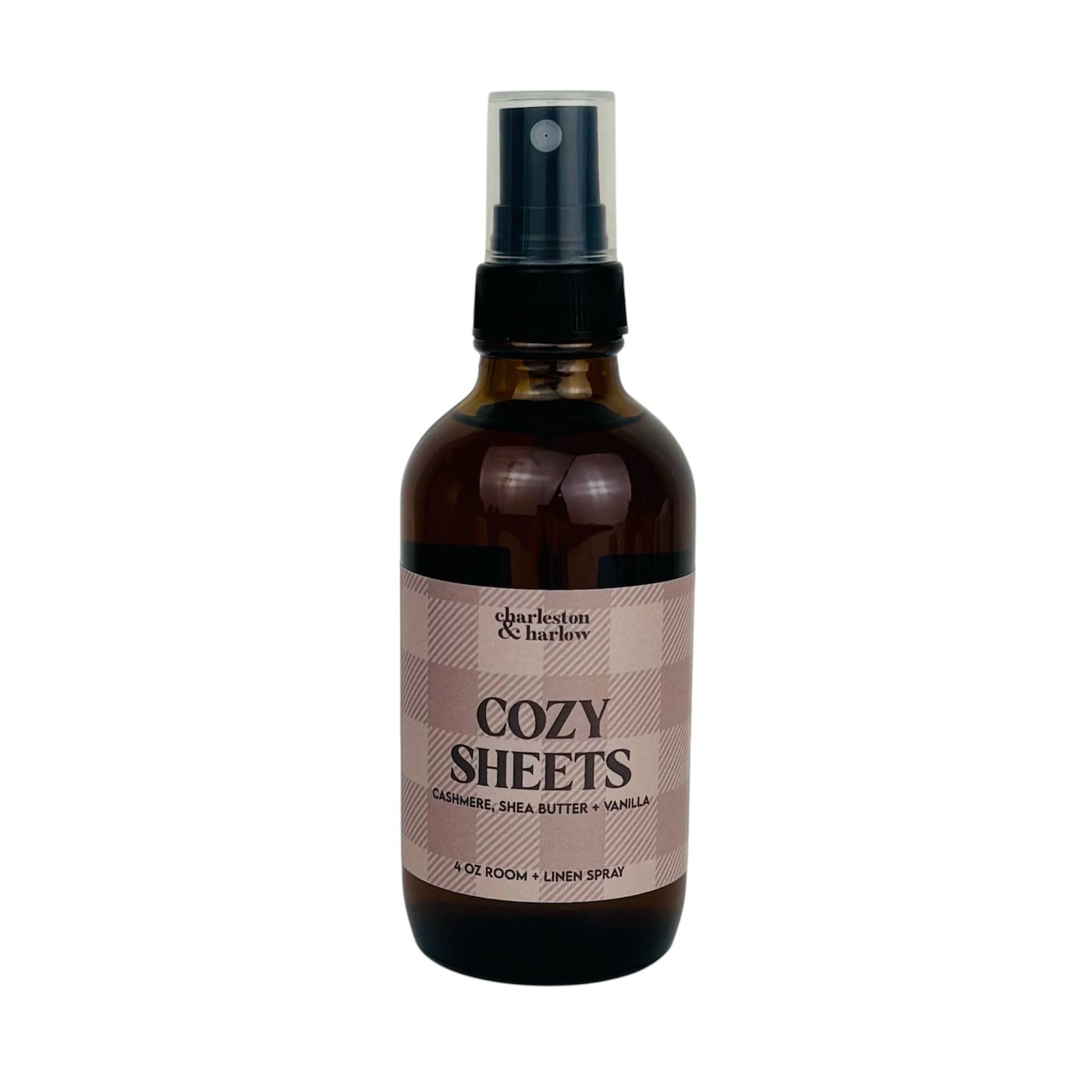 Amber glass spray bottle of Charleston & Harlow Cozy Sheets room and linen spray with tan buffalo check label