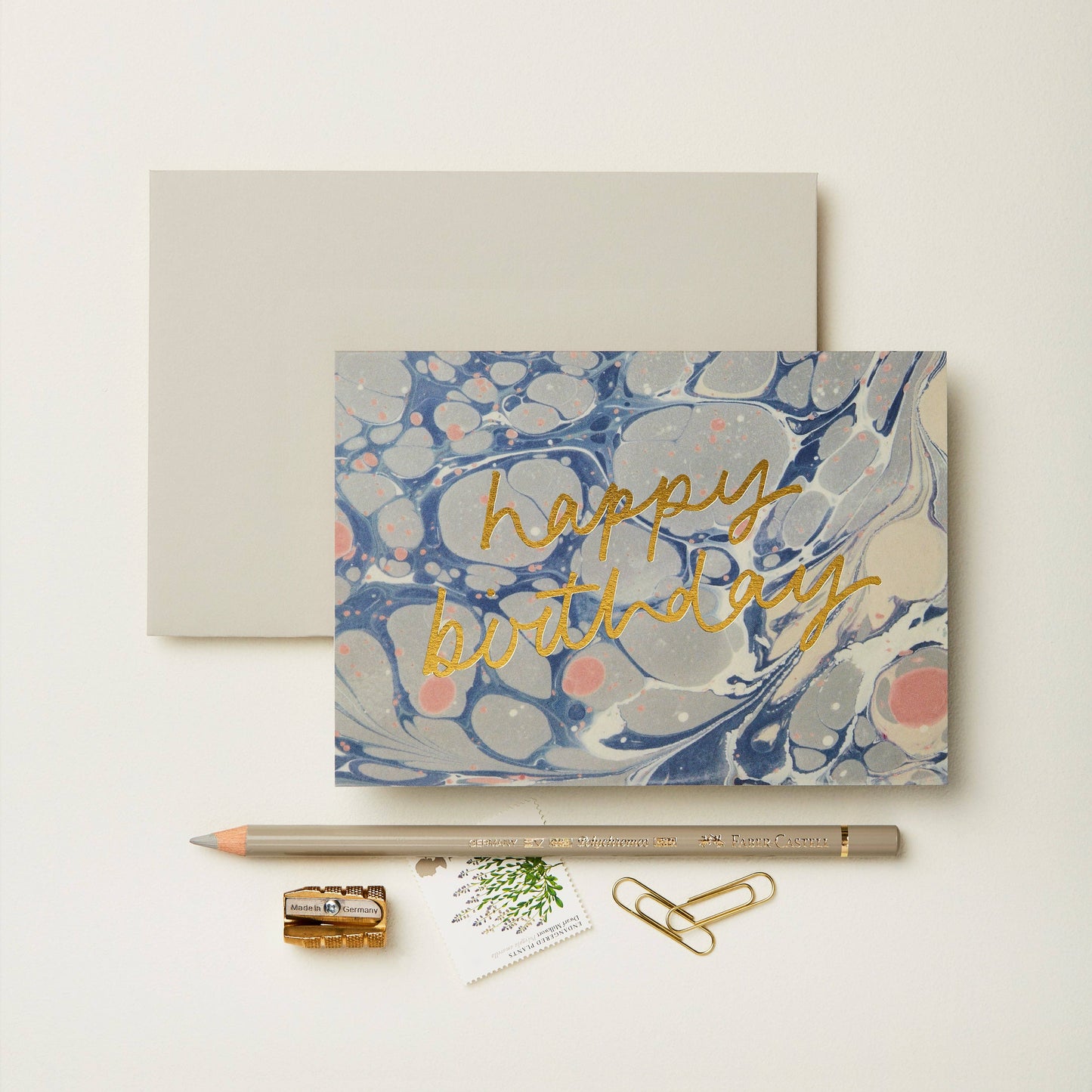 Blue, grey and pink marbled card reading happy birthday in gold script