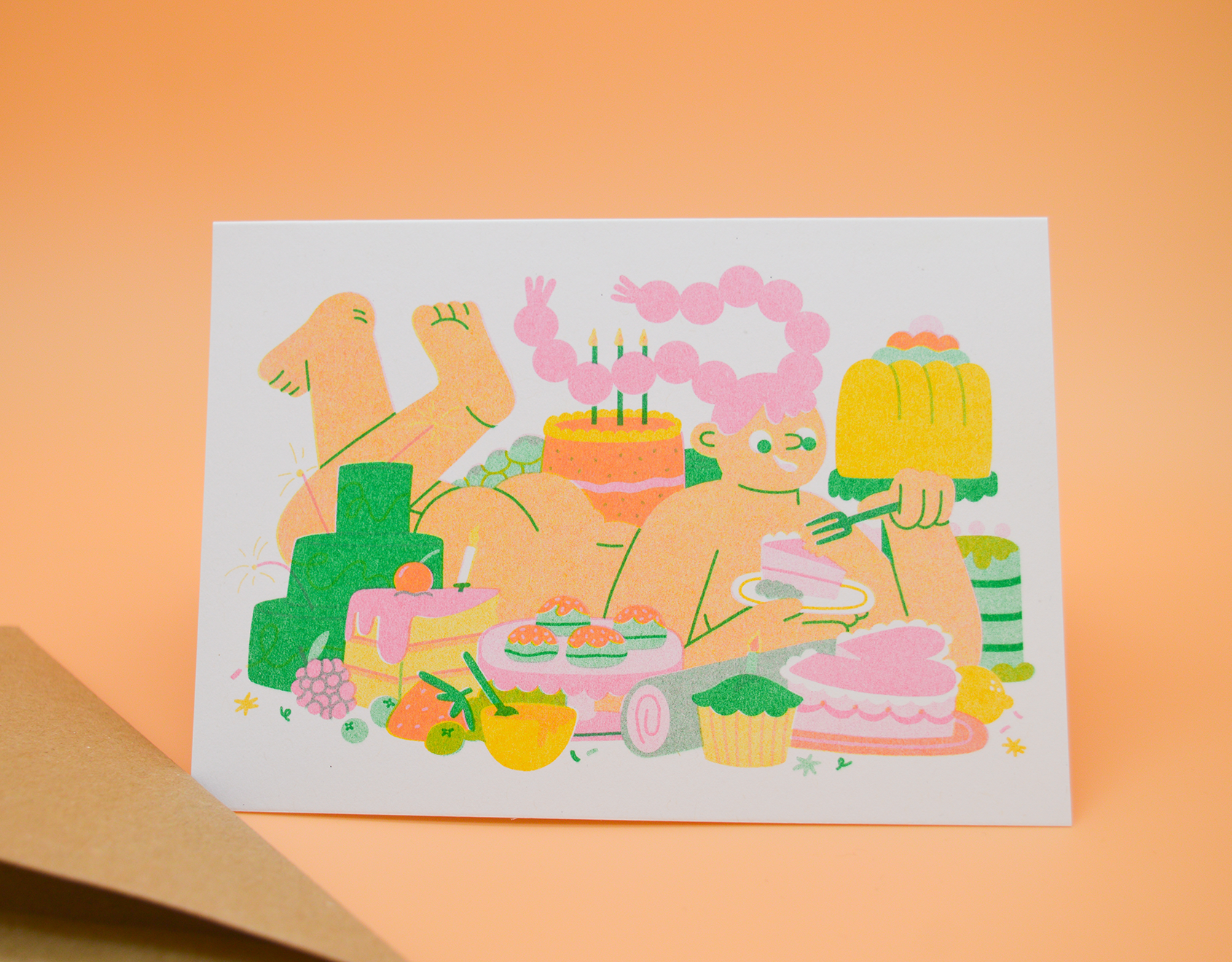 Let Me Eat Cake A6 Card — illustration of a figure surrounded by cakes and desserts, shown with a kraft envelope