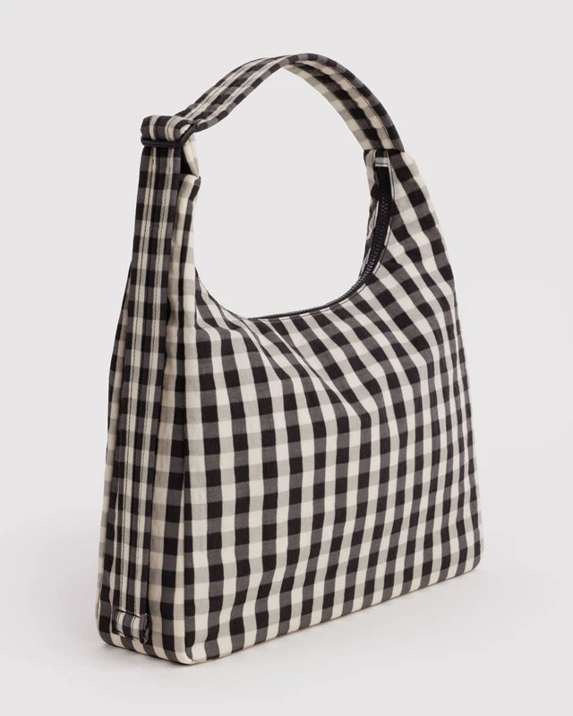 BAGGU Nylon Shoulder Bag in black and cream gingham worn on the shoulder for scale