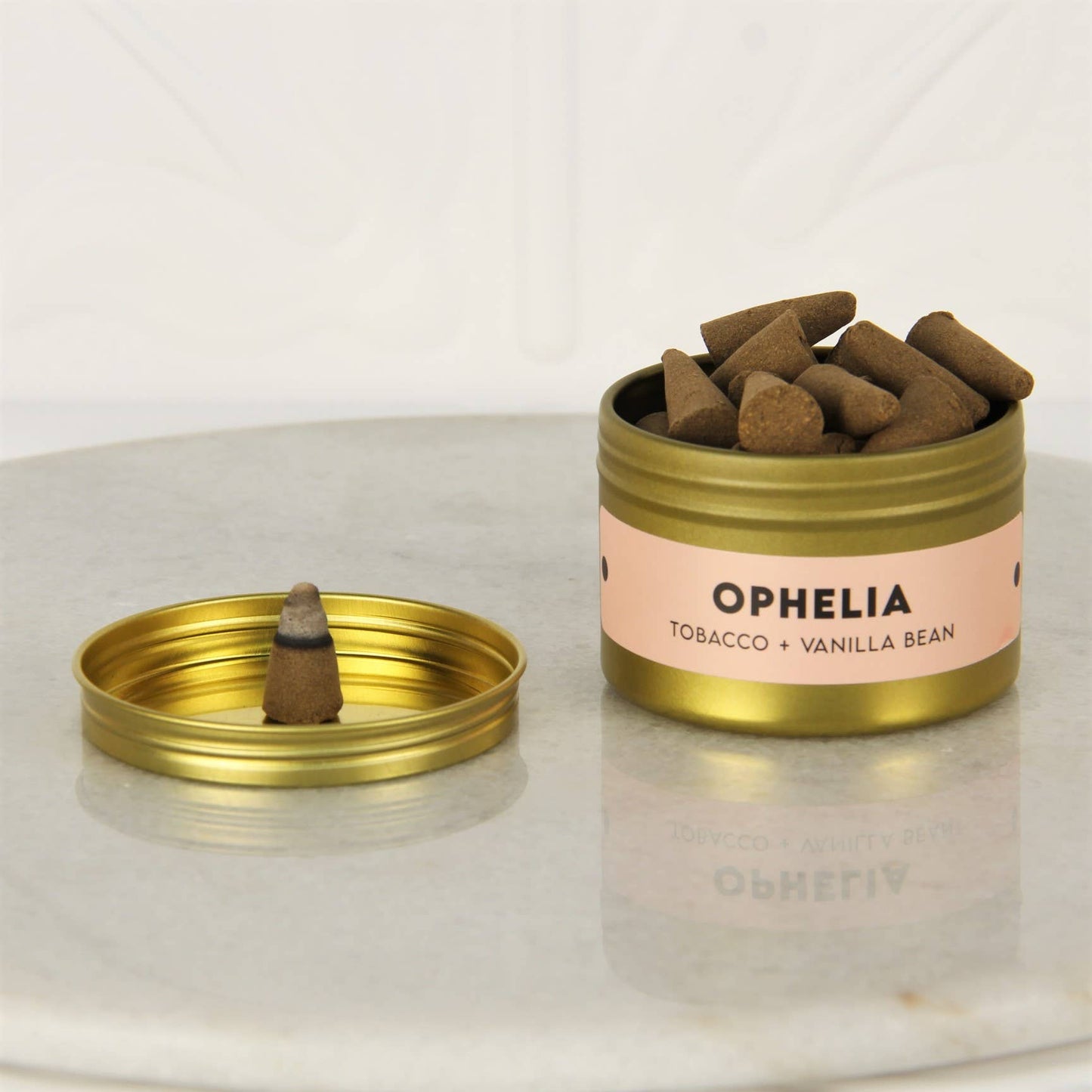 Open gold tin of Charleston & Harlow Ophelia incense cones with peach label, a cone resting on the lid