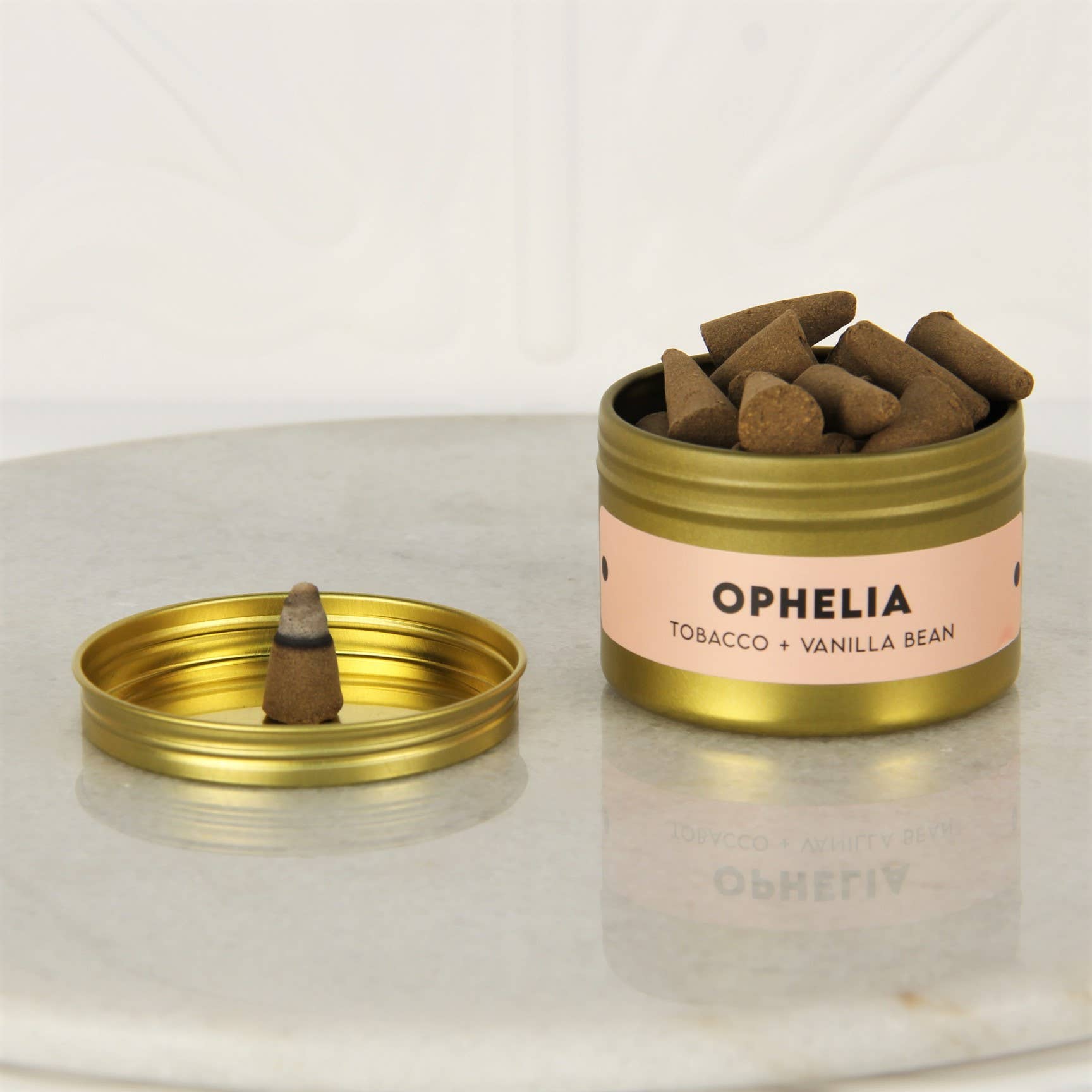 Open gold tin of Charleston & Harlow Ophelia incense cones with peach label, a cone resting on the lid