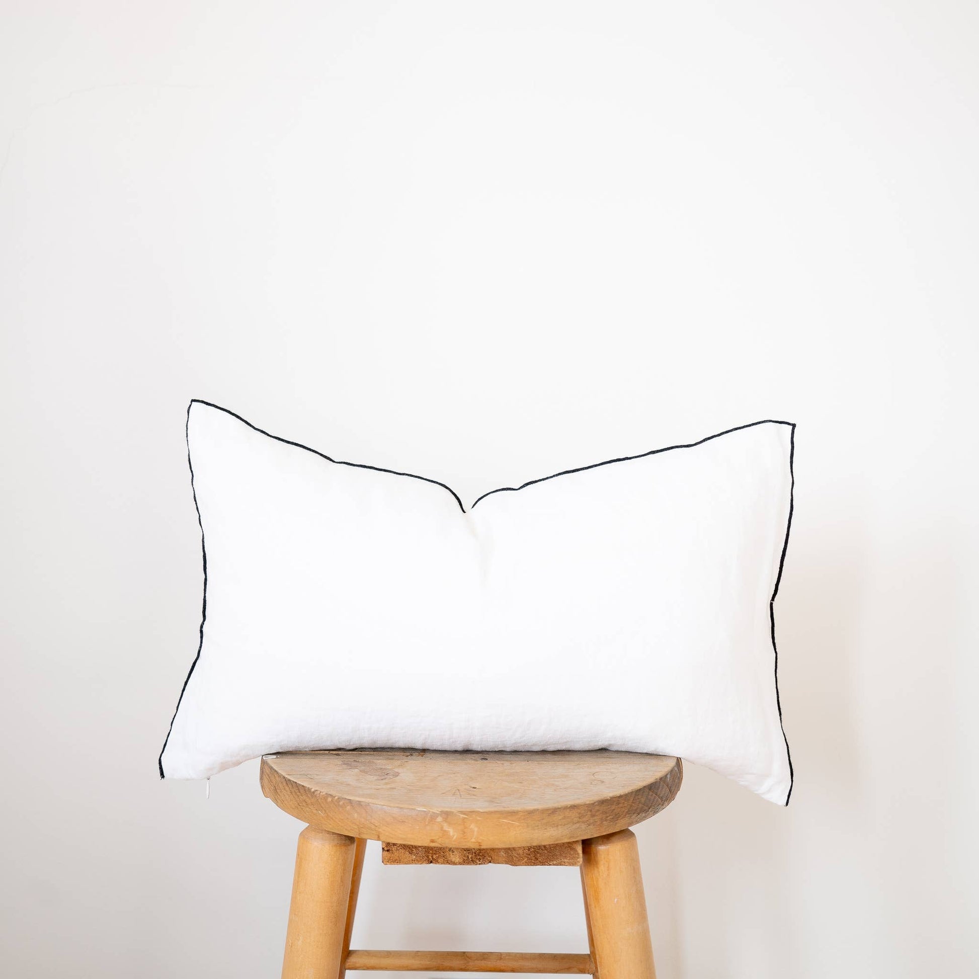 White edged linen lumbar pillow cover styled on a bed