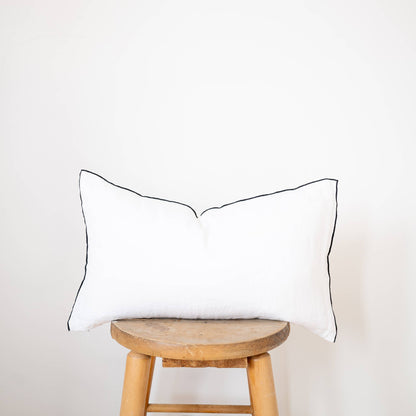 White edged linen lumbar pillow cover styled on a bed