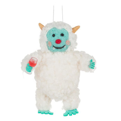 White wool felt yeti ornament with a turquoise face and feet, holding a small wine glass filled with red wine, smiling with rosy cheeks.