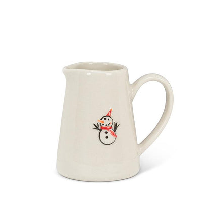 Small cream stoneware jug with a curved handle, hand-illustrated with a snowman wearing a red hat and scarf on the front.