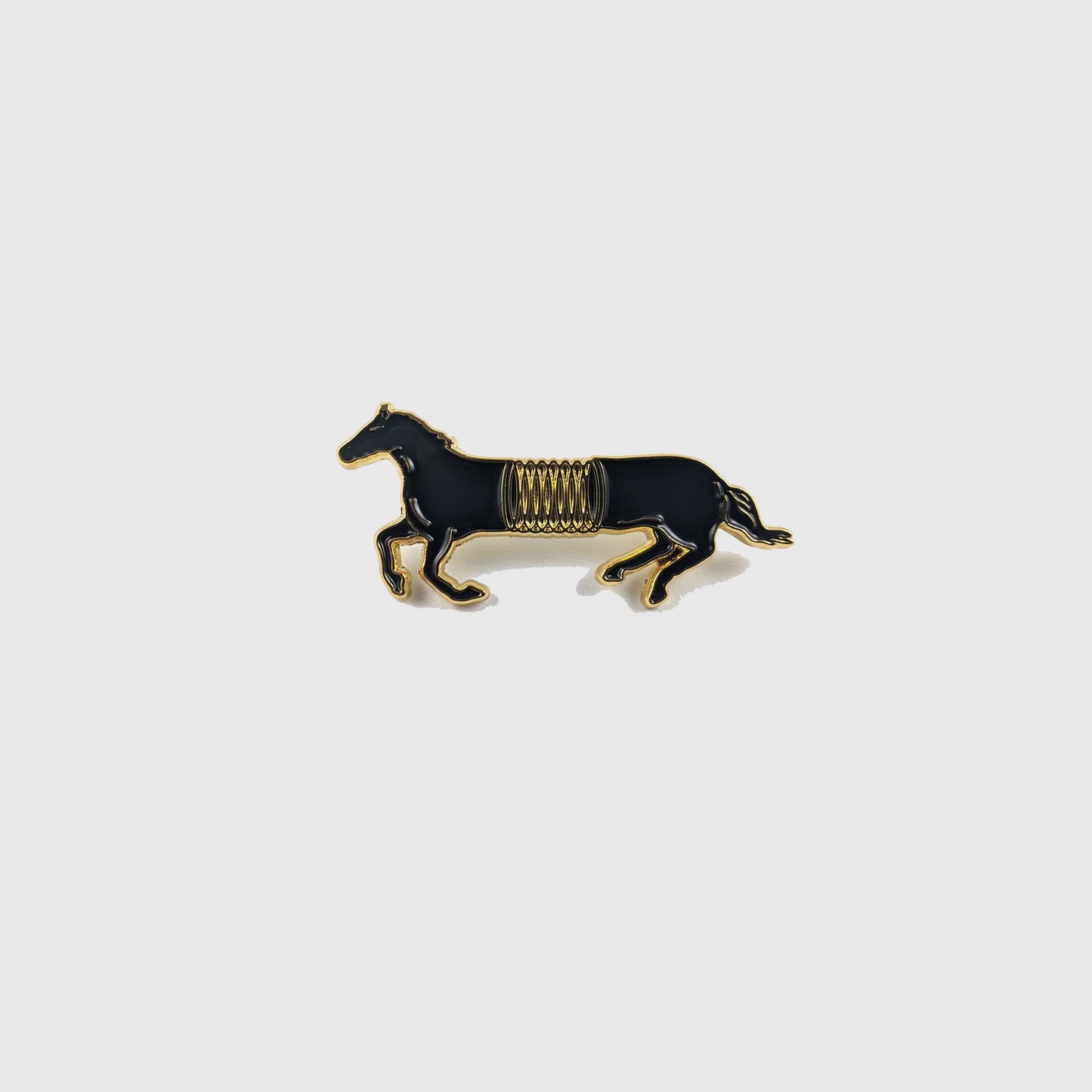 Black and gold enamel pin of a horse mid-gallop with a spring coiled around its middle - PABOOM
