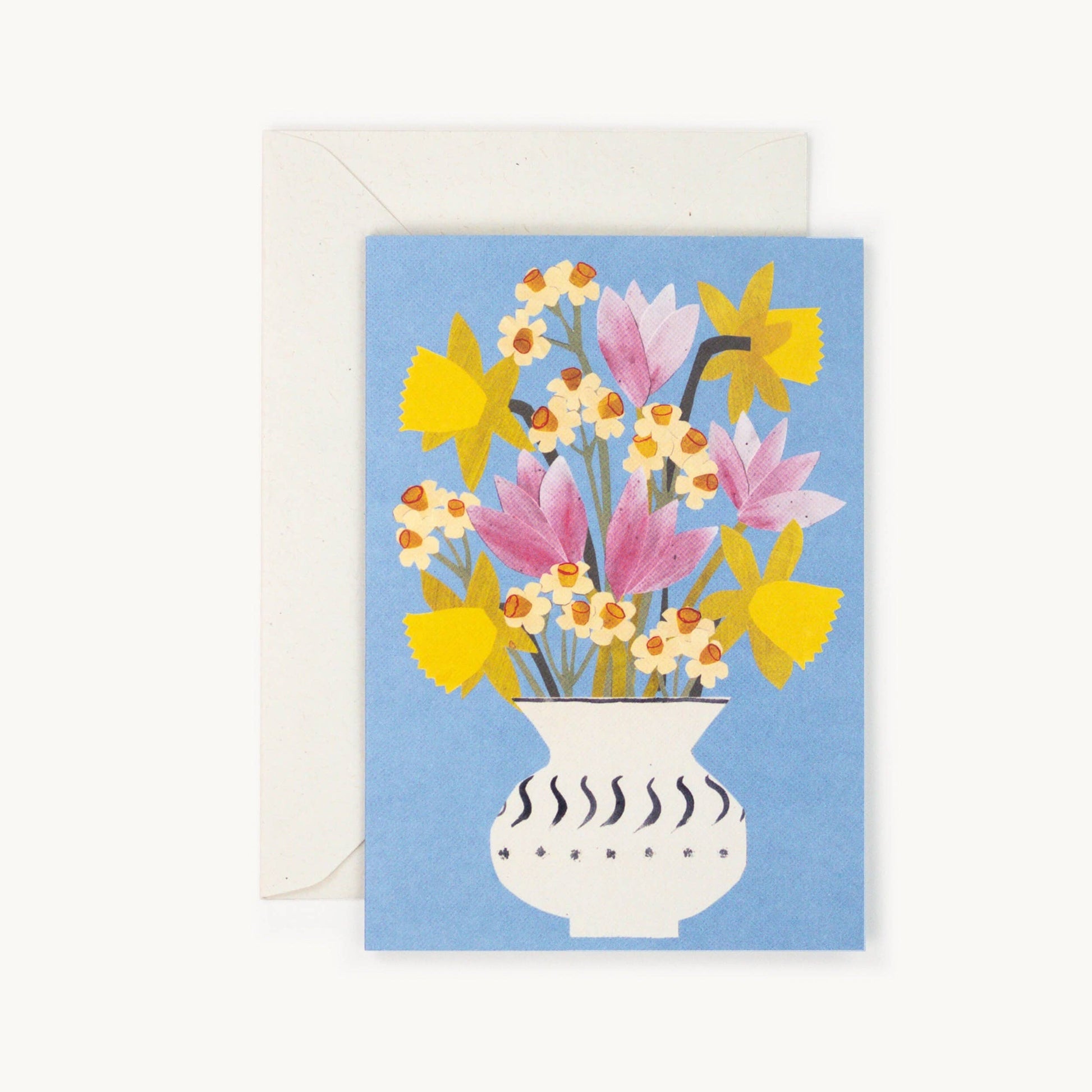 Cornflower blue greeting card with an illustrated white patterned vase holding pink tulips, yellow daffodils and cream narcissus flowers