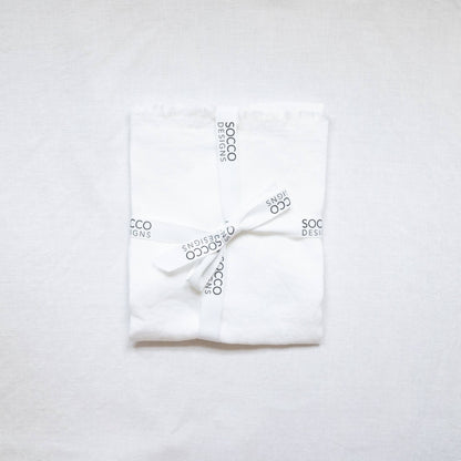 Close-up of the white fringed linen lumbar pillow cover showing the frayed edge texture