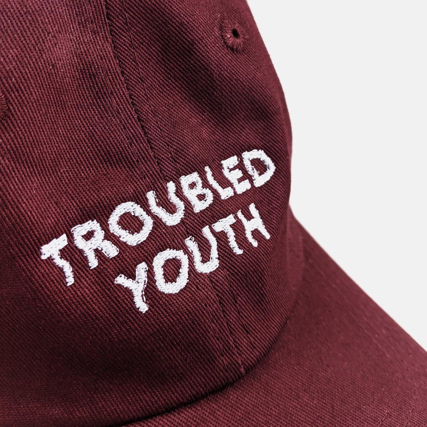 Side view of Troubled Youth burgundy dad hat showing adjustable metal clasp - PABOOM