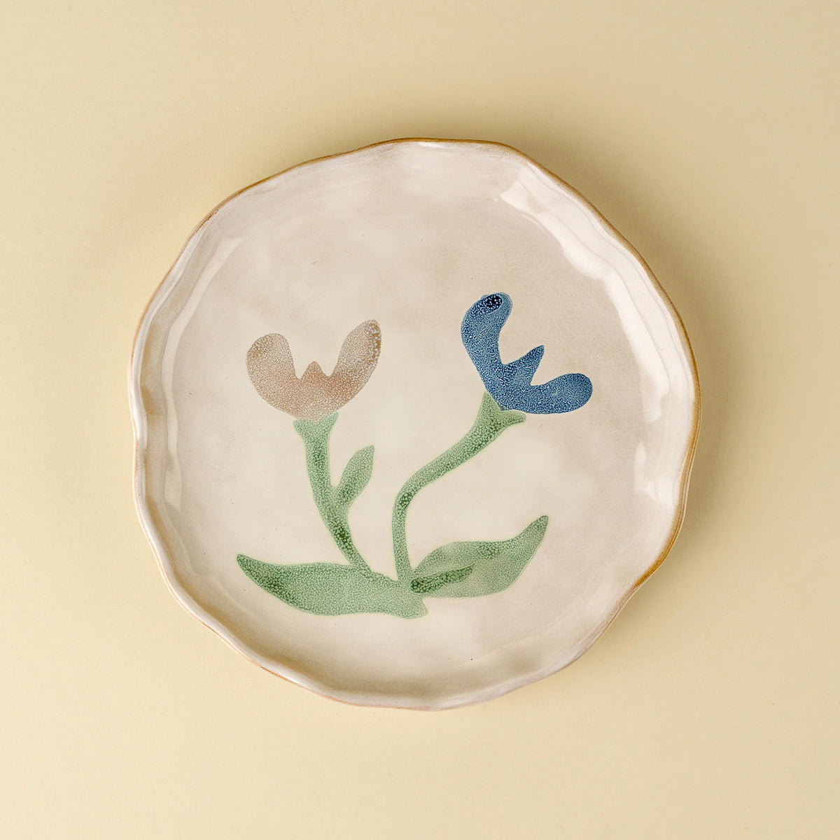 Cream stoneware plate hand-painted with pink and blue florals and a dotted blue rim