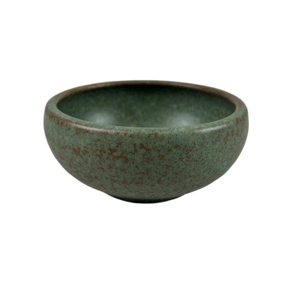 Speckled sage green matte porcelain shallow bowl viewed from a front angle