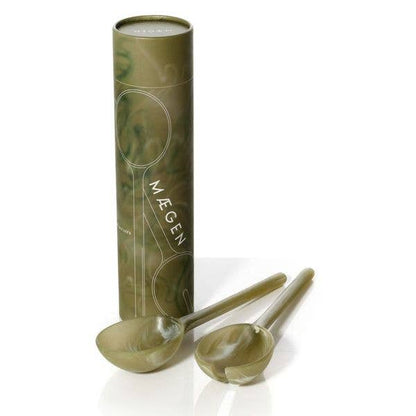 Olive green marbled resin salad server fork and spoon leaning against their MÆGEN cylinder packaging