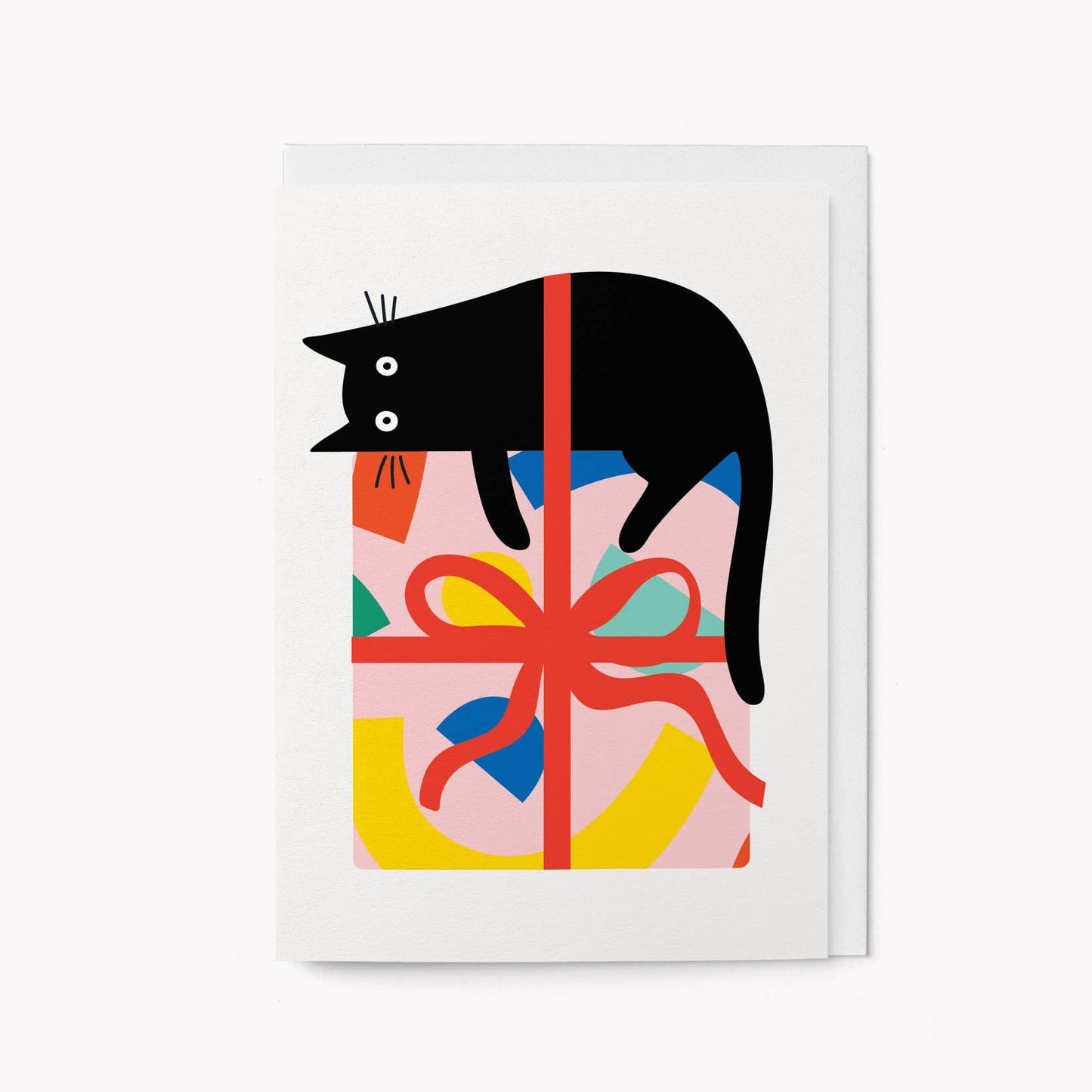 White greeting card with an illustrated black cat lying across a pink gift box wrapped in red ribbon with a colourful pattern