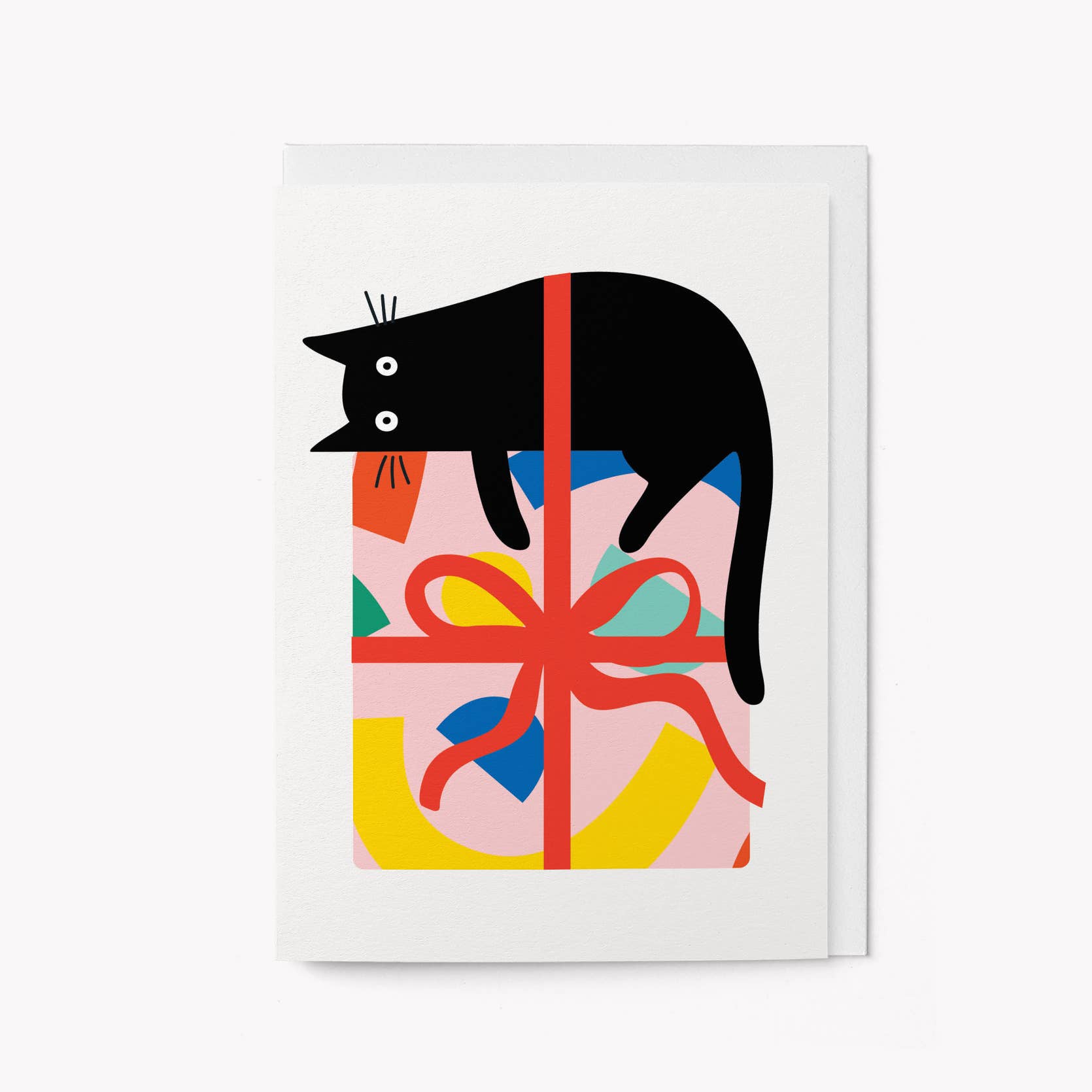 White greeting card with an illustrated black cat lying across a pink gift box wrapped in red ribbon with a colourful pattern